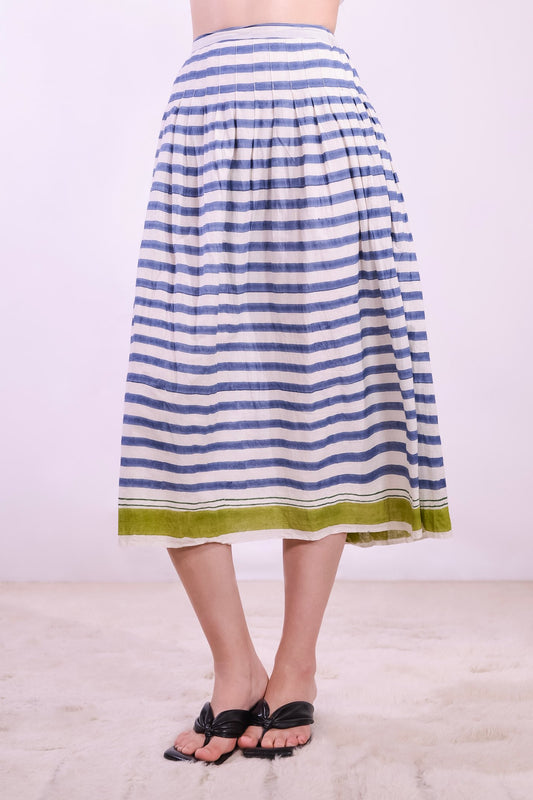 Model wearing a long pleated pure cotton skirt with indigo and off-white stripes, elastic waistband, and pistachio hem. Handcrafted in India by Injiri.