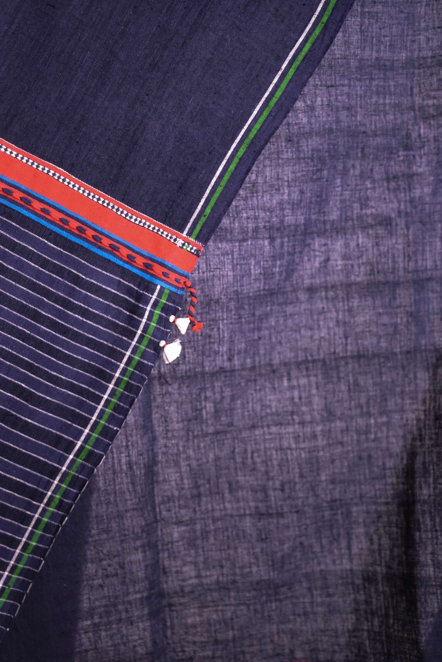 Model wearing pure cotton scarf by Injiri – handloomed unisex accessory in natural indigo with red and white woven details, crafted from organic cotton and finished with tassels. Ethically handmade in India