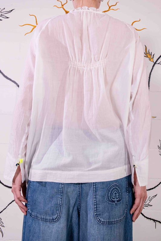 Model wearing Amber 38 pure cotton shirt by Injiri. Long-sleeved white handwoven mousseline cotton shirt with jamdani weaving, stitched detailing, and yellow tassels. Ethically handcrafted in Jaipur, India, and available at House of Woven Stories.