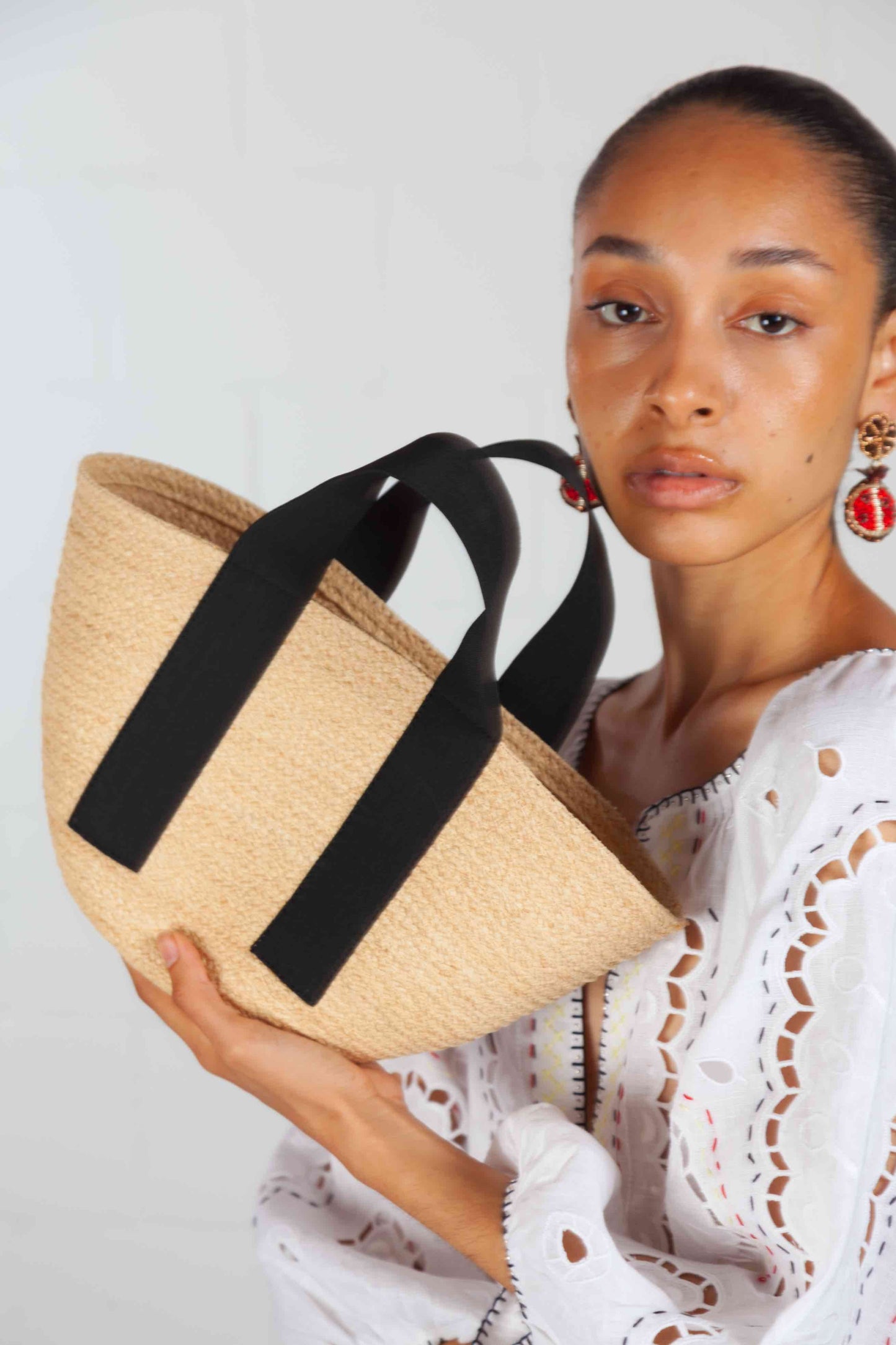 Black Mini Market raffia bag by Lola Hats with elastic handles and stitched raffia tape design. Available at House of Woven Stories.