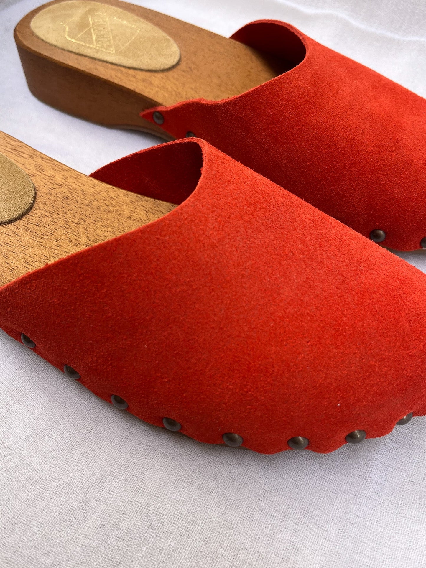 Handmade candy red clogs by Antidoti with studded sides and wooden sole, crafted in Florence, Italy. Available at House of Woven Stories.