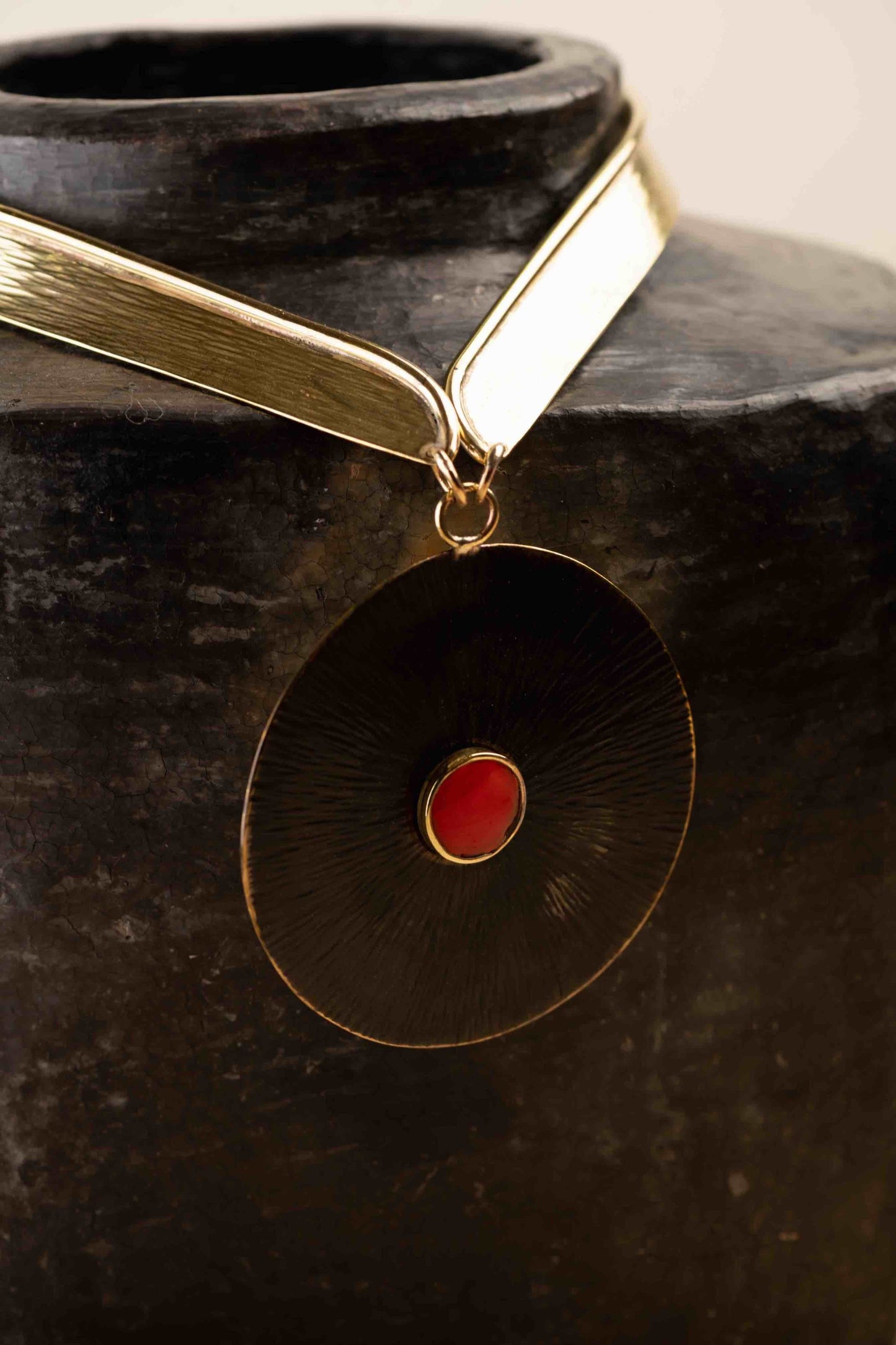 Collier Lacet necklace by Stéphane Szendy, handcrafted hammered bronze with coral-colored geometric enamel pendant, blending traditional craftsmanship with contemporary design. Part of House of Woven Stories selection.