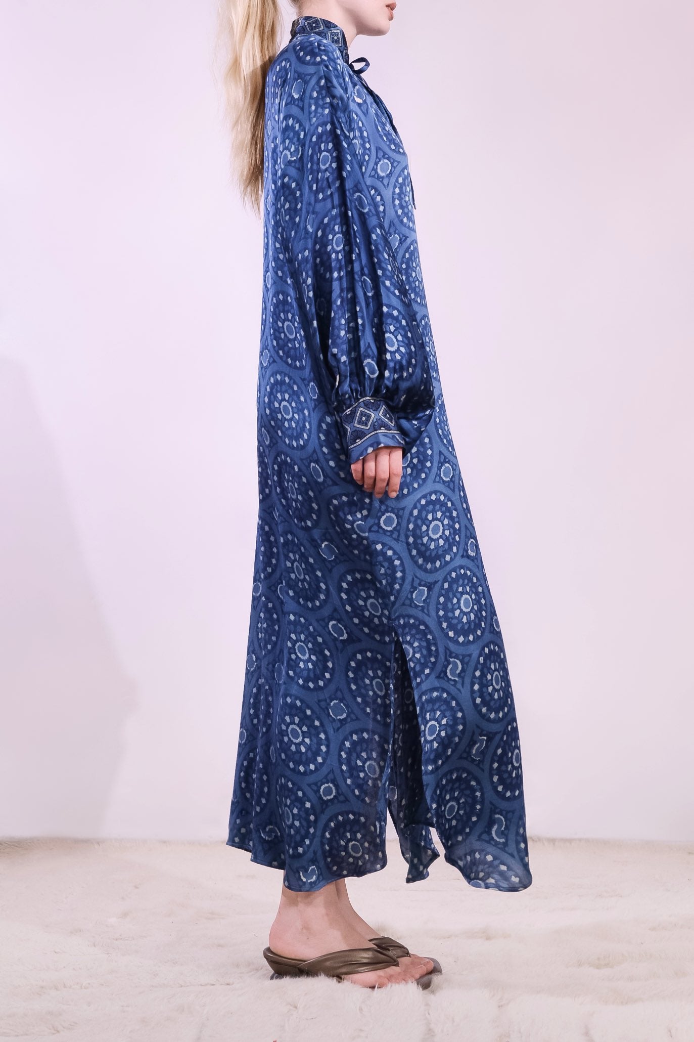 Model wearing Blue Circles Marion Silk Dress by Obidi. Handprinted silk maxi dress with V-neckline, natural indigo Ajrakh blockprint, side pockets, and fluid silhouette. Ethically made in India using traditional techniques.