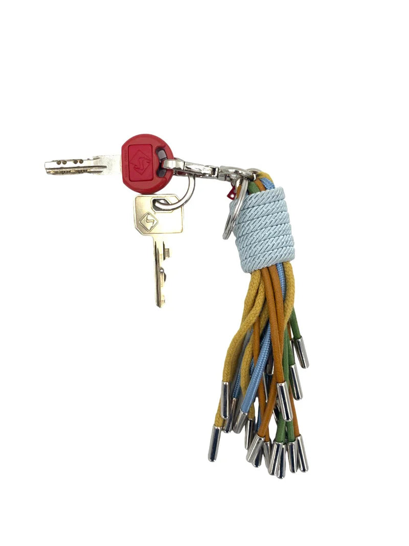 KWAST macramé key ring by MY BOB – handmade in Italy with flowing threads and rich textures, inspired by Flemish port town heritage. Elegant and artisanal accessory, packaged in a soft cotton bag. Shop now.