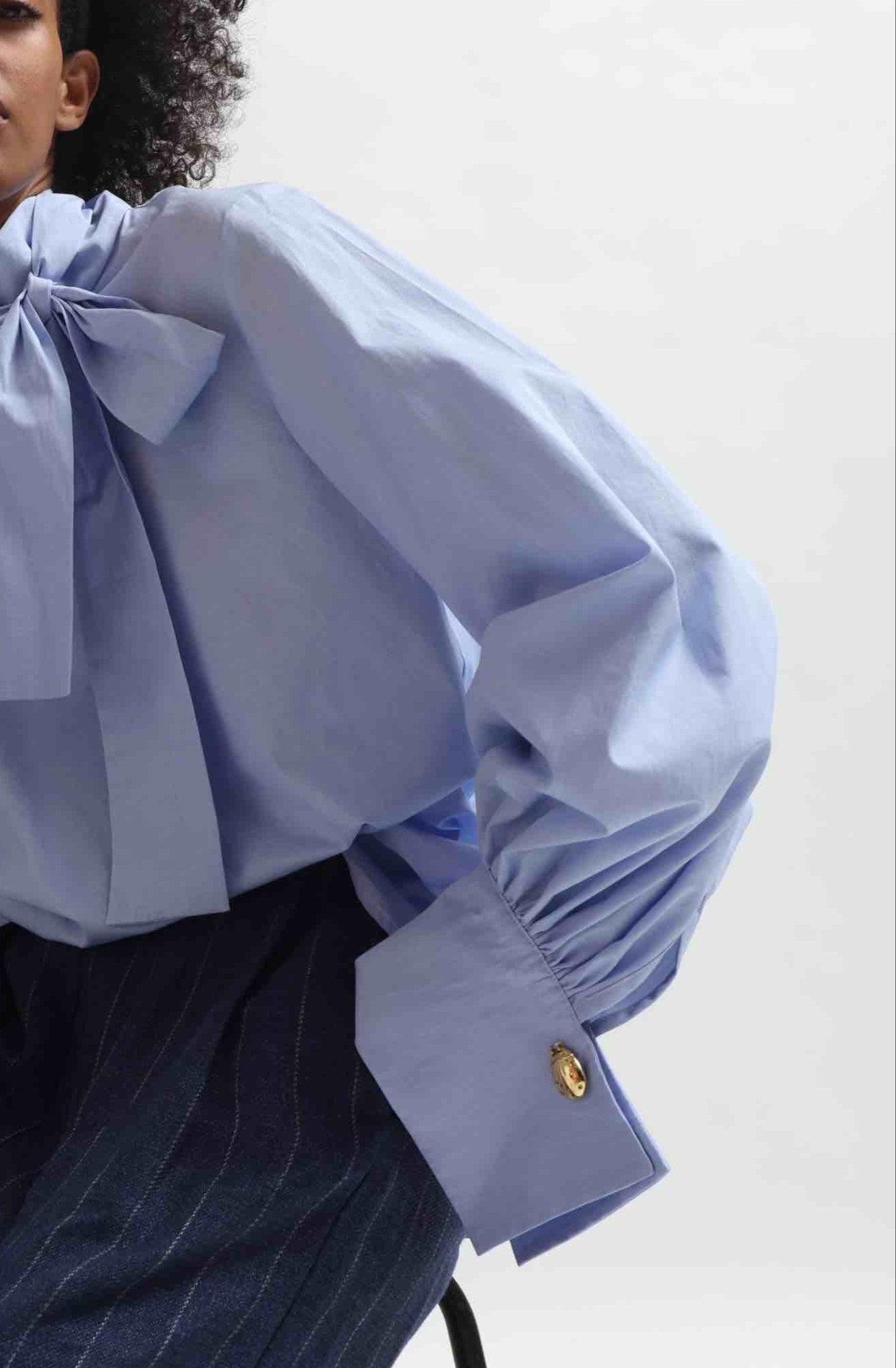 Sky Blue organic cotton blouse by House of Woven Stories, featuring a signature adjustable tie-neck detail. Ethically made in Italy in small batches from soft, premium poplin.