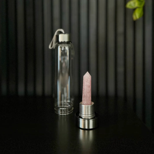 Rose Quartz Crystal Water Bottle by The Goddess Collective, featuring a natural crystal obelisk inside a glass bottle with stainless steel lids and carry sleeve.
