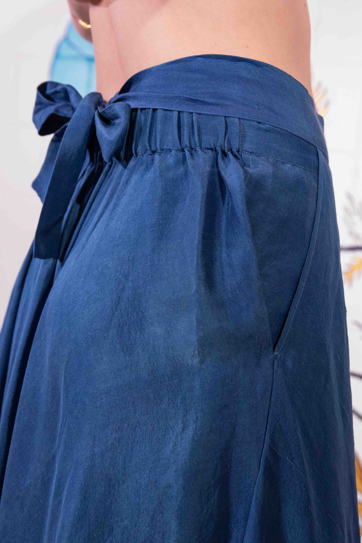 Model is wearing an indigo wrap skirt in naturally dyed silk by A Sacred Wrap, featuring a fluid bias cut, elasticated waistband, and side pockets. Part of House of Woven Stories selection.