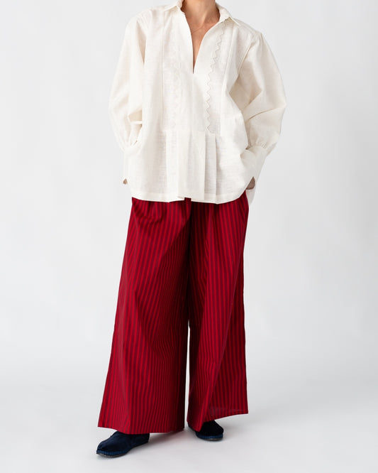 Model is wearing the Ancestral White Linen Shirt by Les Vacances d’Irina, a unisex handmade linen shirt with relaxed cut, open V-neckline, and natural shell buttons, crafted in Bucharest and available at House of Woven Stories.