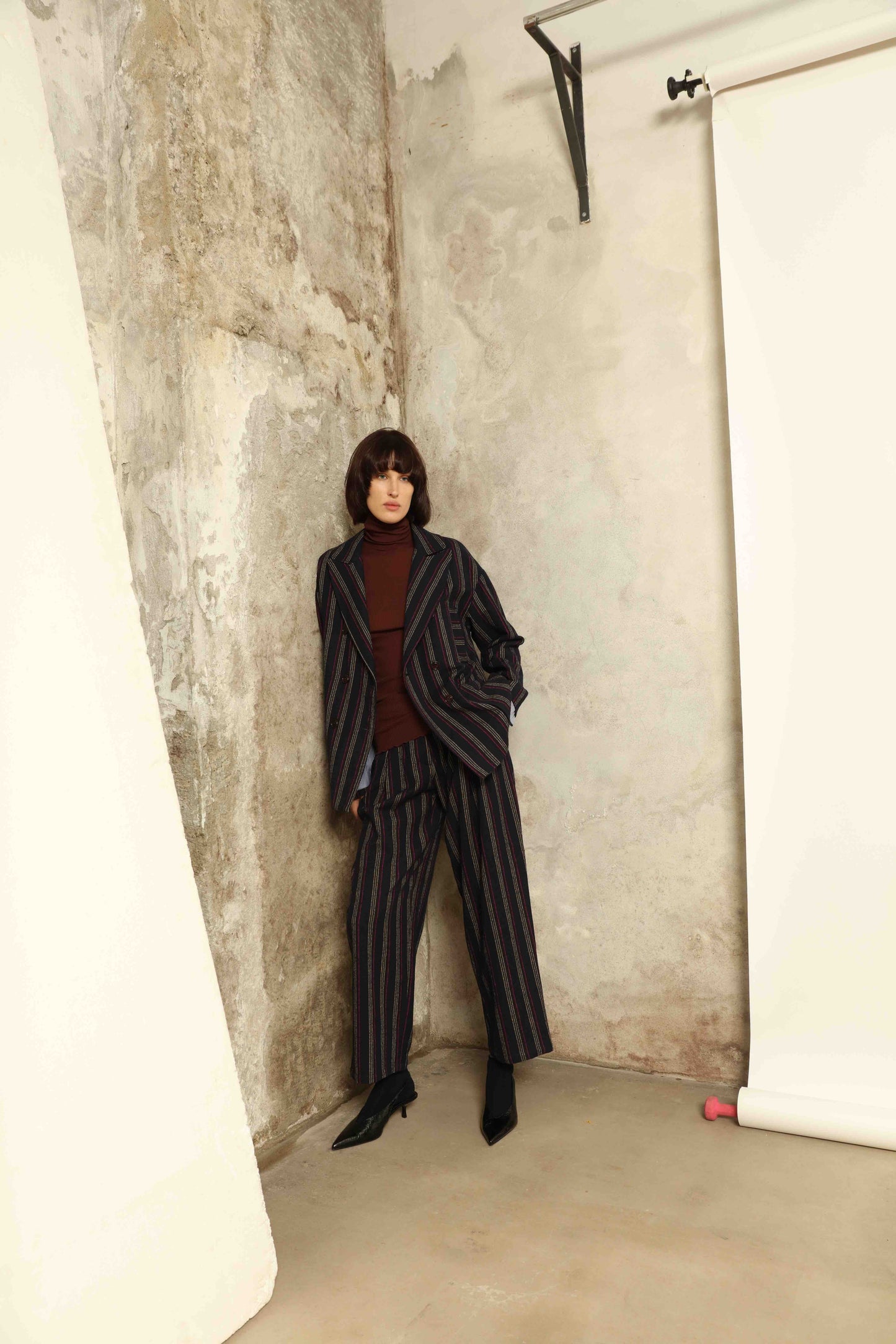 Model is wearing Balia 8.22 navy blue striped trousers made from virgin wool and cotton, tailored fit, Italian craftsmanship, part of House of Woven Stories selection.