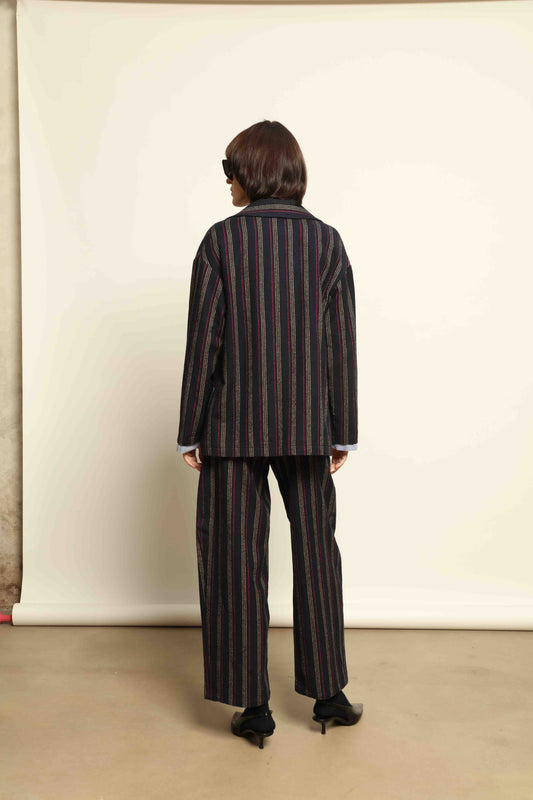 Model is wearing Balia 8.22 navy blue striped trousers made from virgin wool and cotton, tailored fit, Italian craftsmanship, part of House of Woven Stories selection.