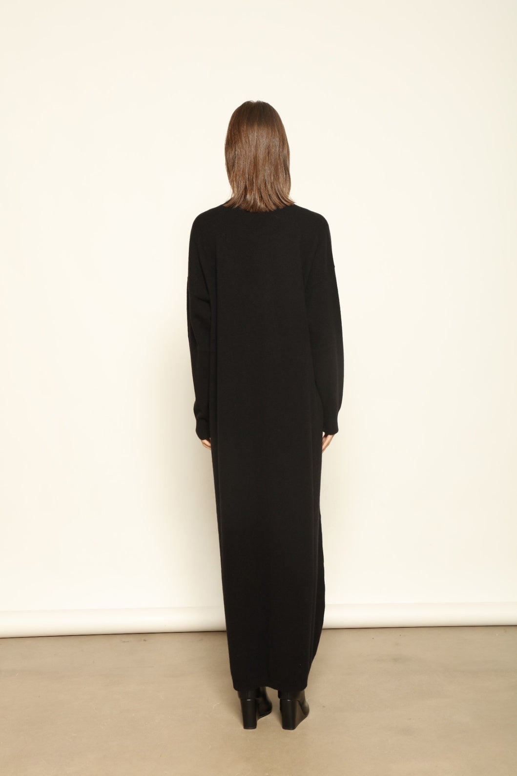 Model wearing the Black Katharina V-Neck Cashmere Maxi Dress by House of Woven Stories, crafted in Italy from 100% pure Inner Mongolia cashmere, featuring a flowing silhouette, soft drape, and timeless sustainable black knitwear design