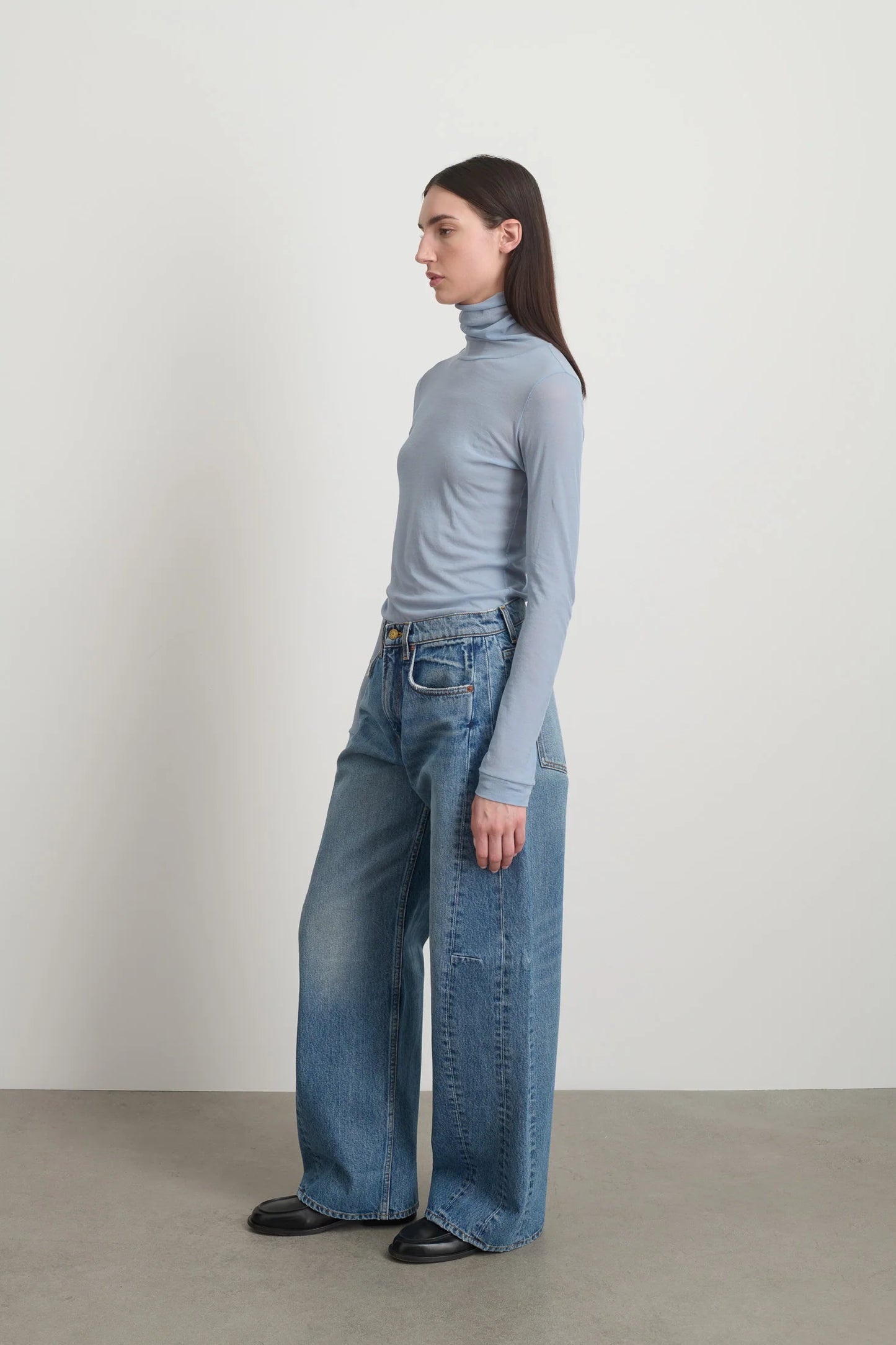 Model is wearing Relaxed Cuffed Lasso Jean Jane Wash by B Sides in pale blue stone washed cotton-rich denim with high waist, pieced outseam, kinked leg and raw hem, available at House of Nomad Stories