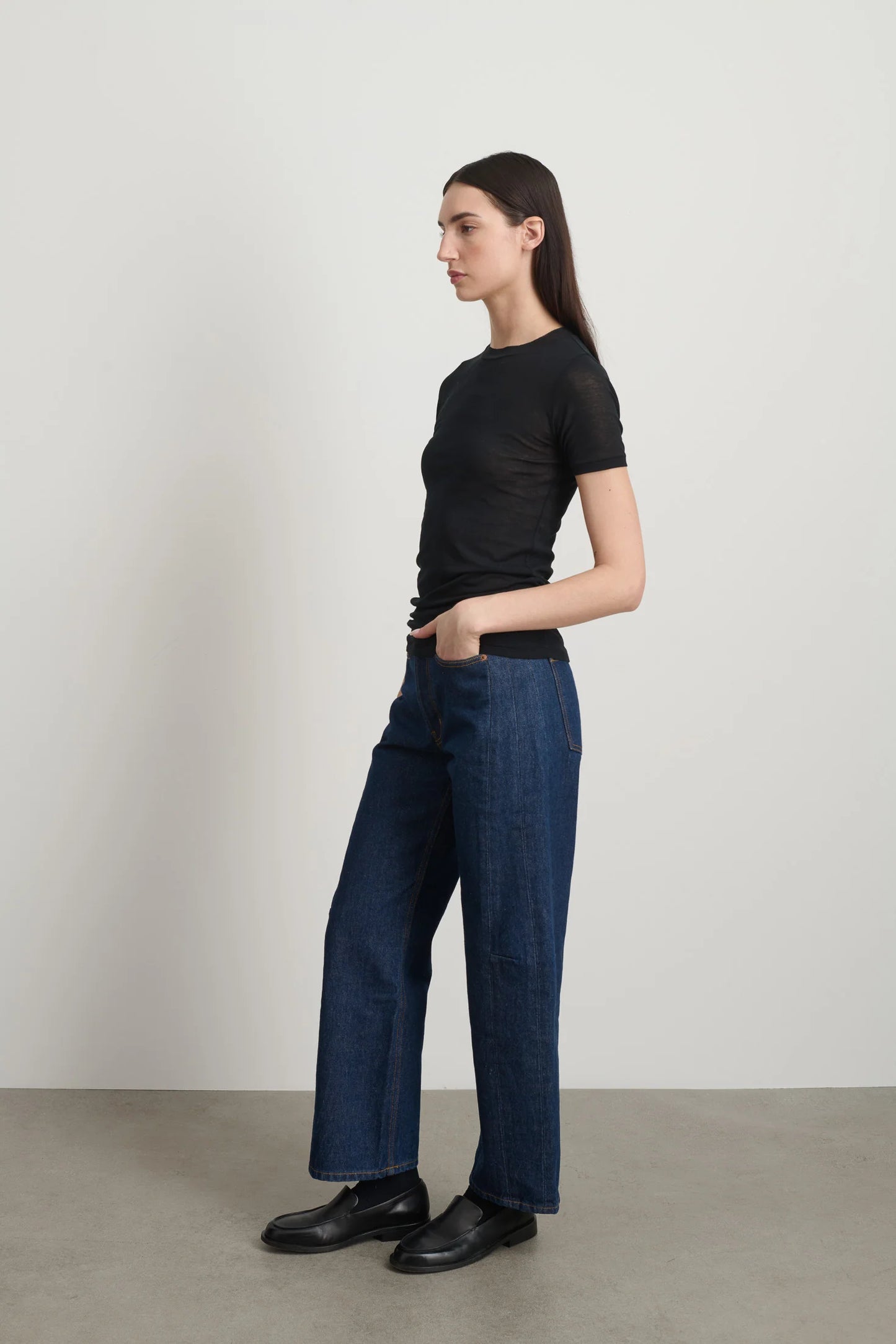 Model is wearing Viven Black Cotton Tee by B Sides in Japanese-milled black rib crepe with slim second-skin fit, short sleeves and crew neck, available at House of Nomad Stories