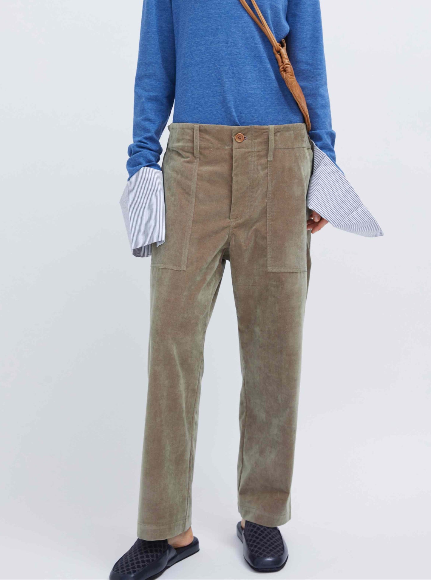 Model is wearing the Camille Pant by Maison Jejia, part of the House of Woven Stories selection, featuring a straight-leg fit, taupe velvet fabric, oversized rectangular side pockets, belt loops, and central wooden button.