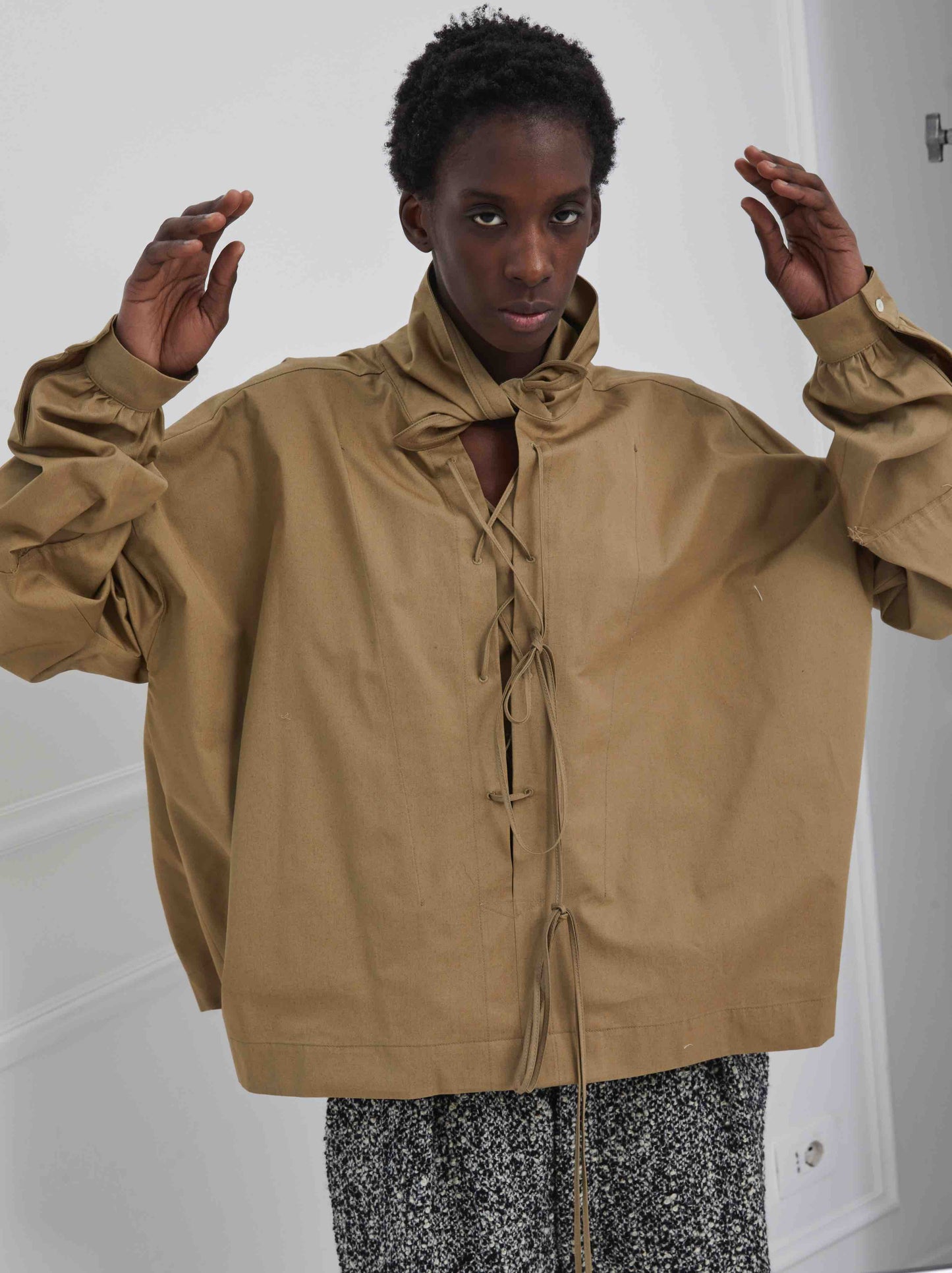 Model is wearing the Ceci Beige Shirt by Maison Jejia, part of the House of Woven Stories selection, featuring an oversized fit, structured beige fabric, and versatile styling options.
