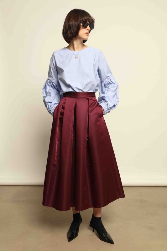 Model is wearing the Duchesse Violet Skirt by Lunatica Milano in mirtillo purple with box pleats and a flowing, elegant silhouette.