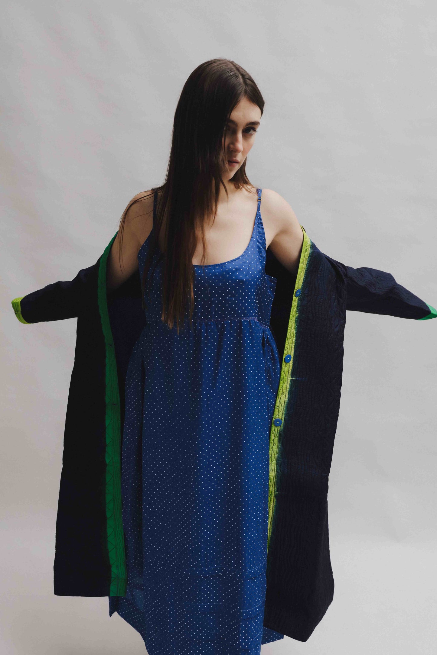Model is wearing the Folklore 18 handmade silk coat by Injiri, featuring a navy blue exterior, green lining, 100% silk, and luxurious artisan craftsmanship.