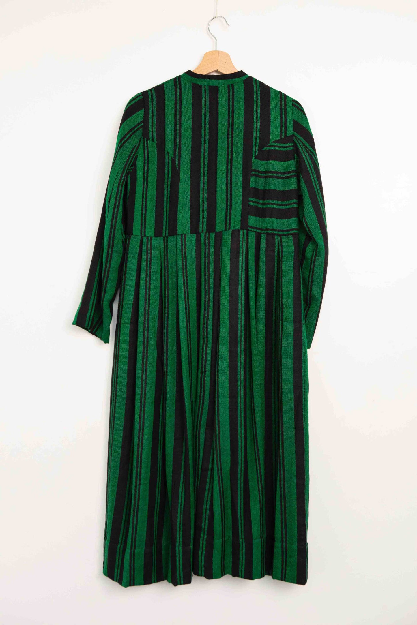 Model is wearing the Folklore 34 silk and wool striped dress by Injiri, featuring bold green and black stripes and sky blue buttons, artisan-made in India.