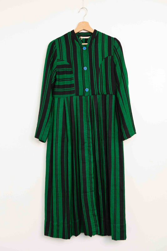 Model is wearing the Folklore 34 silk and wool striped dress by Injiri, featuring bold green and black stripes and sky blue buttons, artisan-made in India.