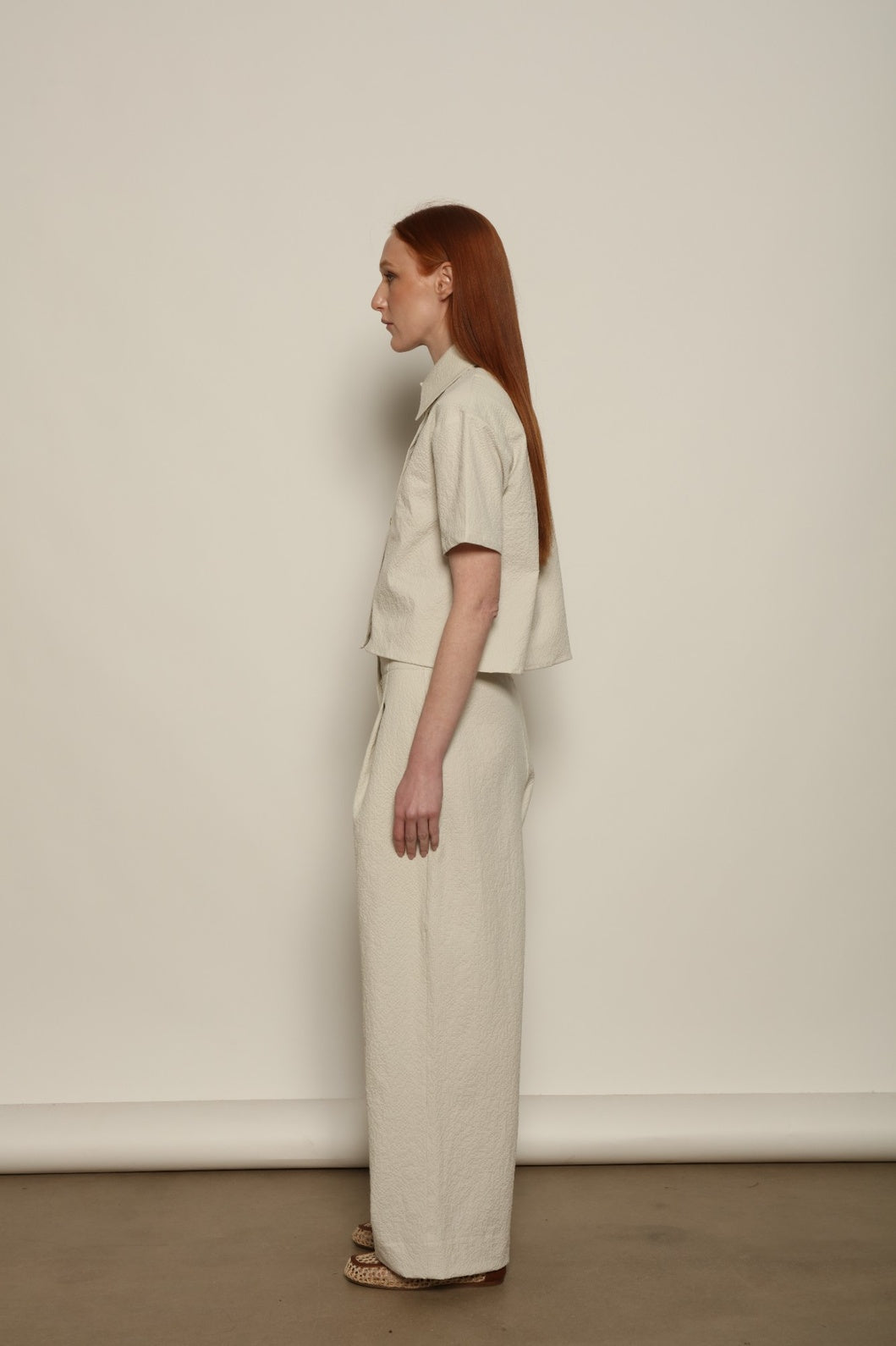 Model is wearing the Gabriella seersucker trousers from the House of Woven Stories selection, lightweight and breathable women’s summer pants made in Italy, featuring a relaxed tailored silhouette designed for effortless movement and warm weather.