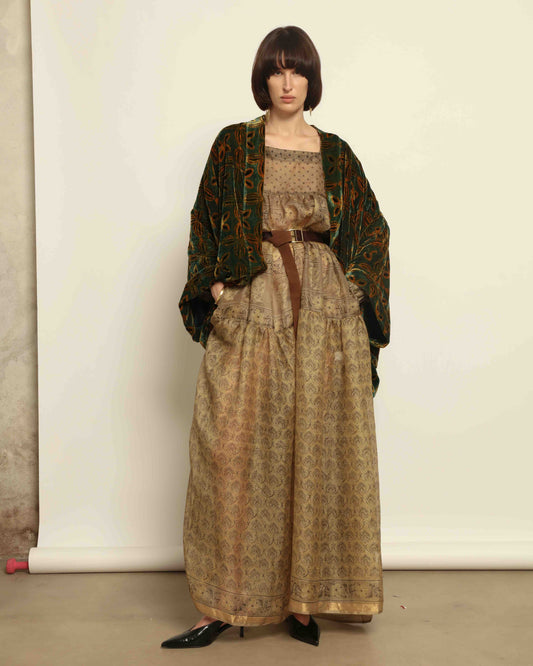 Model is wearing a golden sage silk and velvet abaya with geometric patterns, featuring a flowing elegant silhouette, perfect for modern and regal styling.