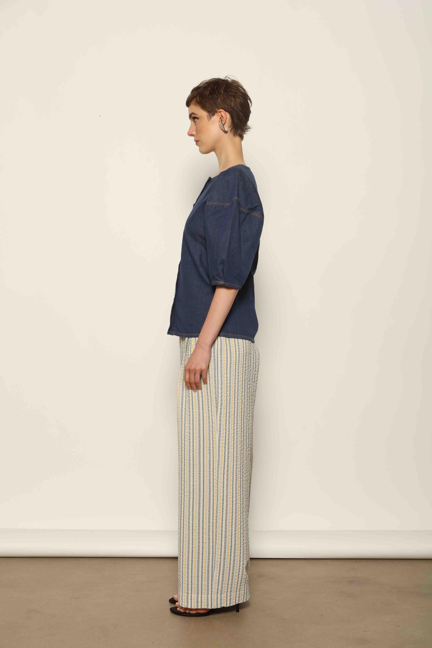 Model wearing the Blouse Bubble Brut in cotton denim by Happy Haus, featuring balloon sleeves, straight-cut silhouette, round neckline, and tobacco topstitching in a lightweight, breathable fabric.