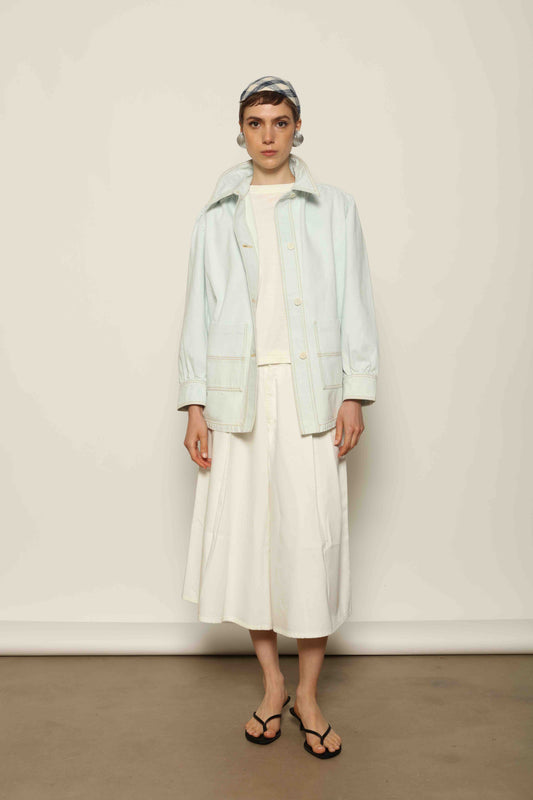 Model wearing the La Veste Peintre in Summer Blue by Happy Haus from the House of Nomad Stories collection, featuring a relaxed fit, light blue denim, patch pockets, wooden button closure, and workwear-inspired design.