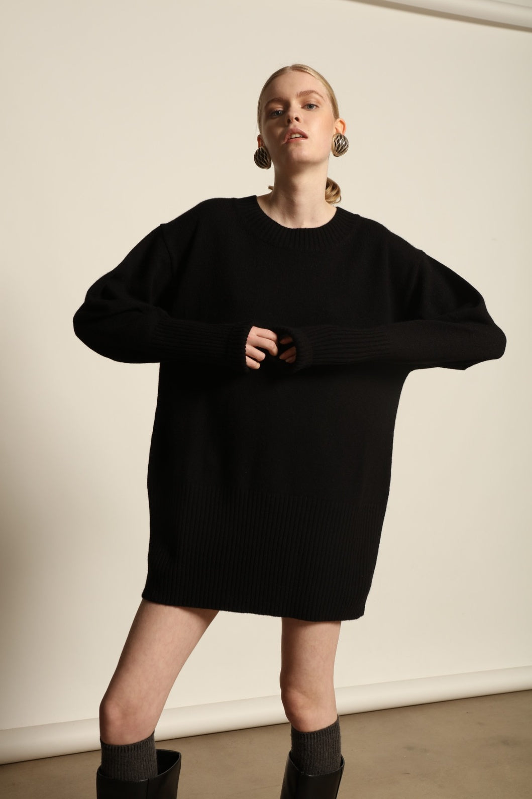 Model is wearing the Black Noemi Round Neck Long Sweater by House of Woven Stories, a pure ethically sourced cashmere knit in deep black with long silhouette, round neckline and ribbed edges.