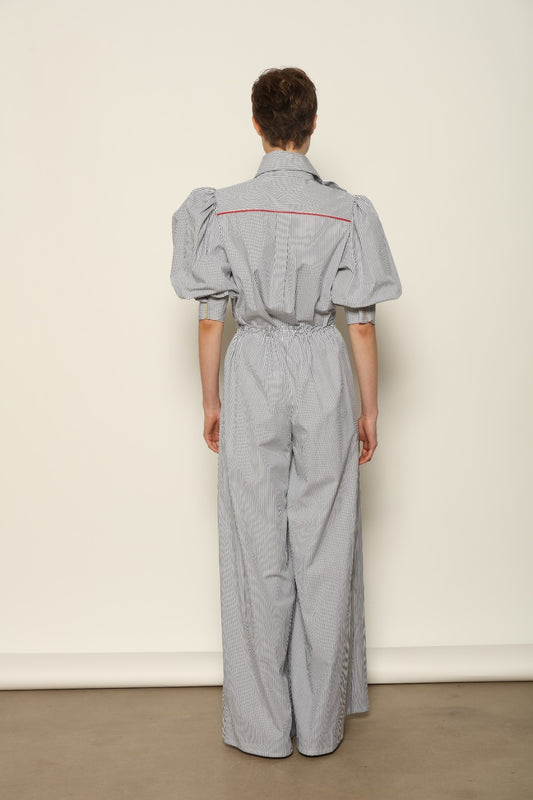 Model wearing the Brigitta White Navy Striped Trousers by House of Woven Stories, featuring 100% organic cotton fabric, high-rise waist, wide-leg silhouette, and classic white and navy stripes.