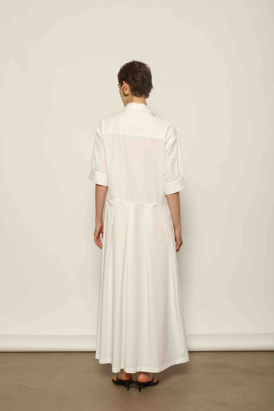 Model wearing the Emily Organic White Cotton Dress by House of Woven Stories, featuring 100% organic cotton fabric, classic collar, button-down front, and adjustable belt for a clean, elegant silhouette.