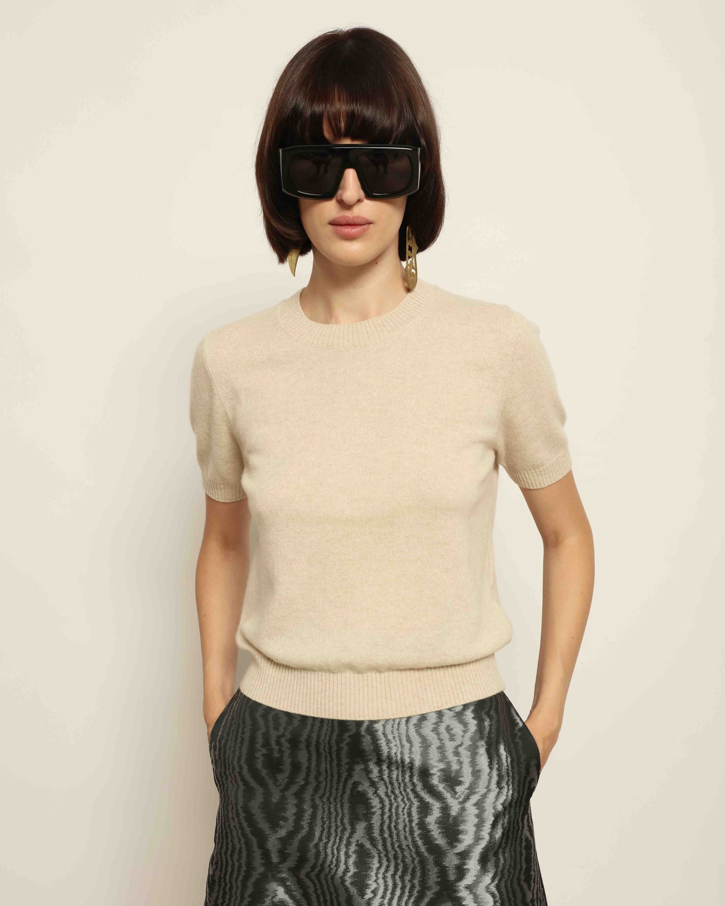 Model is wearing House of Woven Stories Natural Natascha Pullover, round neck, short sleeves, relaxed fit, made from 100% pure cashmere sourced from Inner Mongolia and Tibet, handmade in Italy.