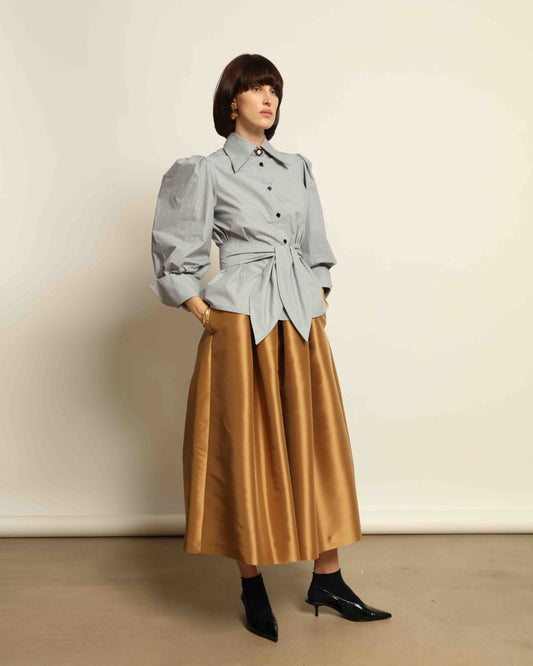 Model is wearing the Karin Micro Check Vichy Cotton Shirt by House of Woven Stories, featuring puffed sleeves, a detachable tie, and a timeless checked design, handmade in Italy from 100% organic cotton.