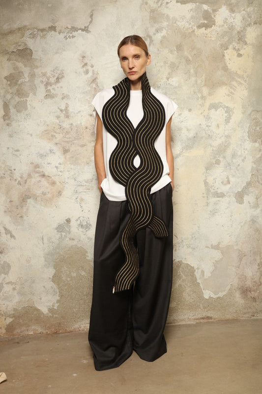 Model is wearing the Coco Curvy Scarf by Ka-Sha, a handcrafted sculptural accessory with curved folds and gold detailing, available in black and gold or white and gold, curated in the House of Woven Stories selection.