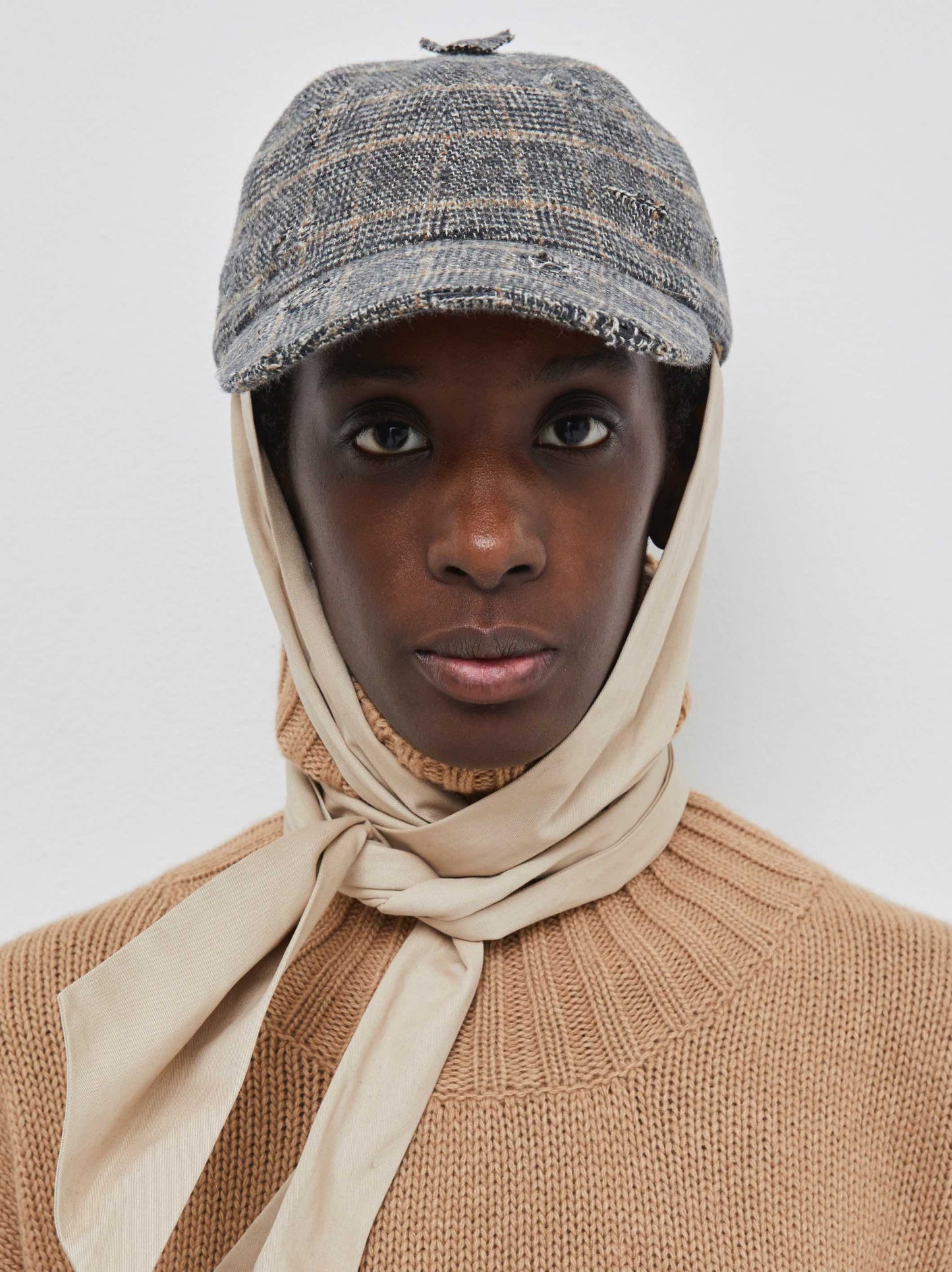Model is wearing the Kate Cotton Check Cap by Maison Jejia, part of the House of Woven Stories selection, featuring premium cotton, classic check pattern, detachable strap, adjustable closure, and three design variations.