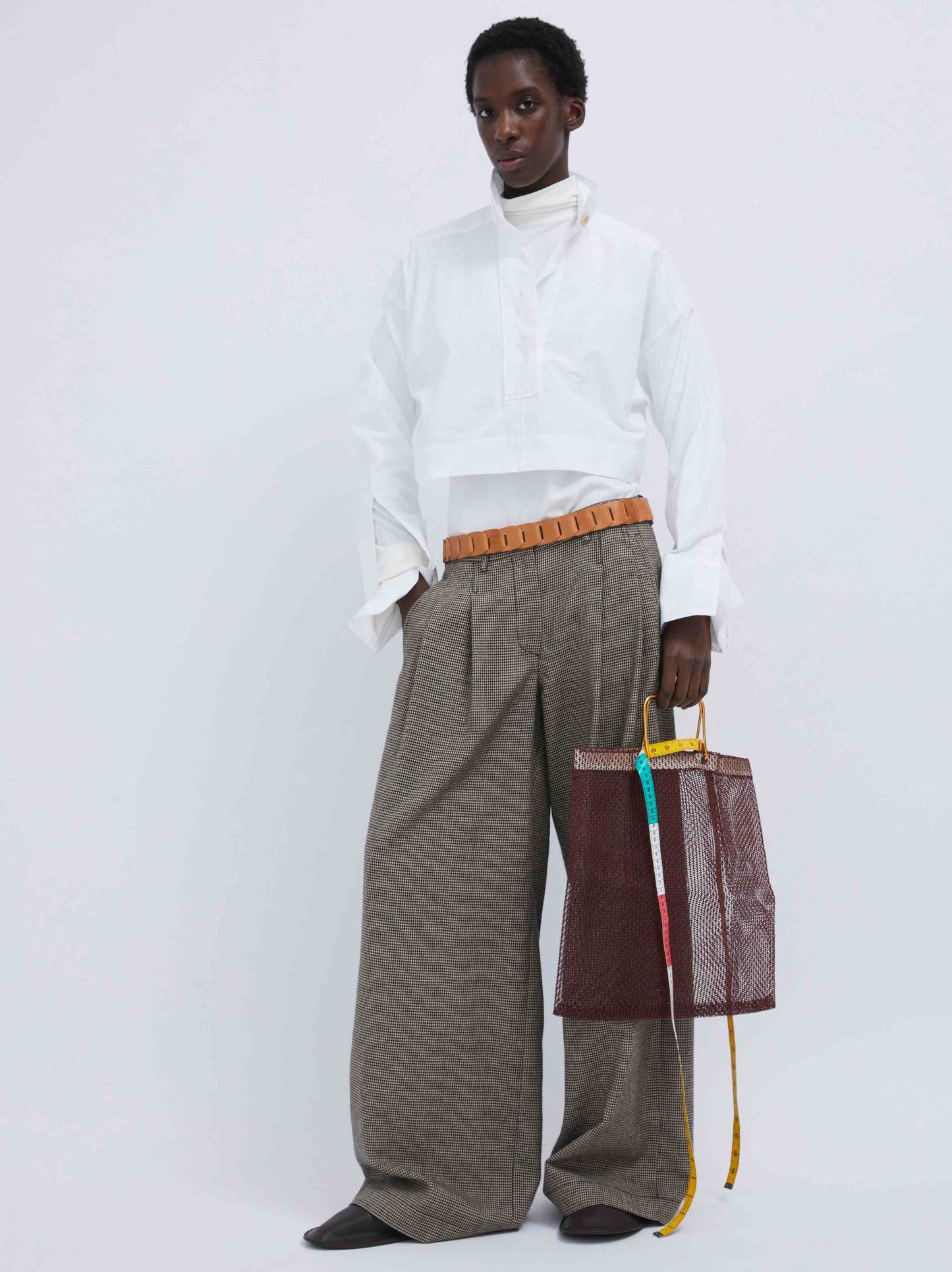 Model is wearing the Katherine Pied de Poule Pant by Maison Jejia, part of the House of Woven Stories selection, featuring a wide-leg fit, houndstooth pattern, front pleats, belt loops, side pockets, and welt pockets with button closures.