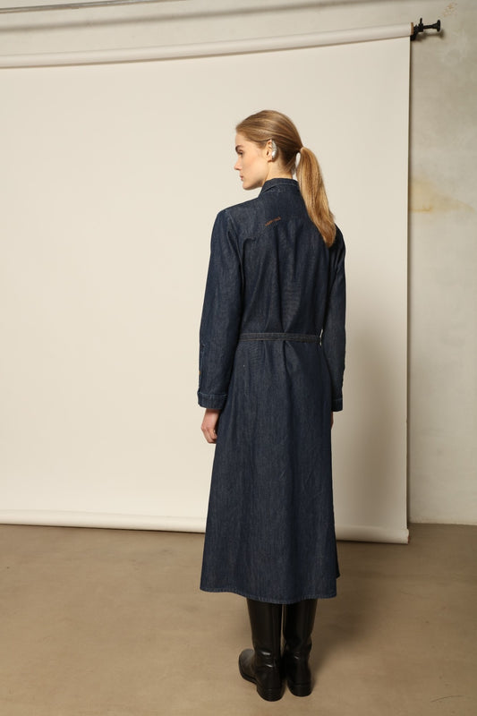 Model is wearing La Robe Star in Bleu D’été by Happy Haus, a denim shirt dress with relaxed fit, chest pockets, matching belt, and golden button detail, combining timeless style with versatile year-round wear.