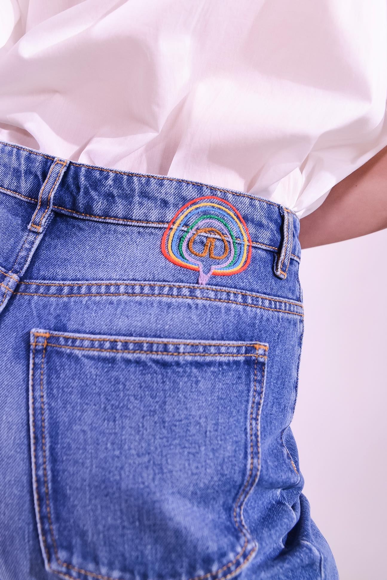 Model is wearing the Le Pantalon Baggy in Bleu d’Été Vintage by Happy Haus - relaxed boyfriend-style recycled denim jeans with wooden button, flower-shaped back pockets, and tobacco-colored topstitching.