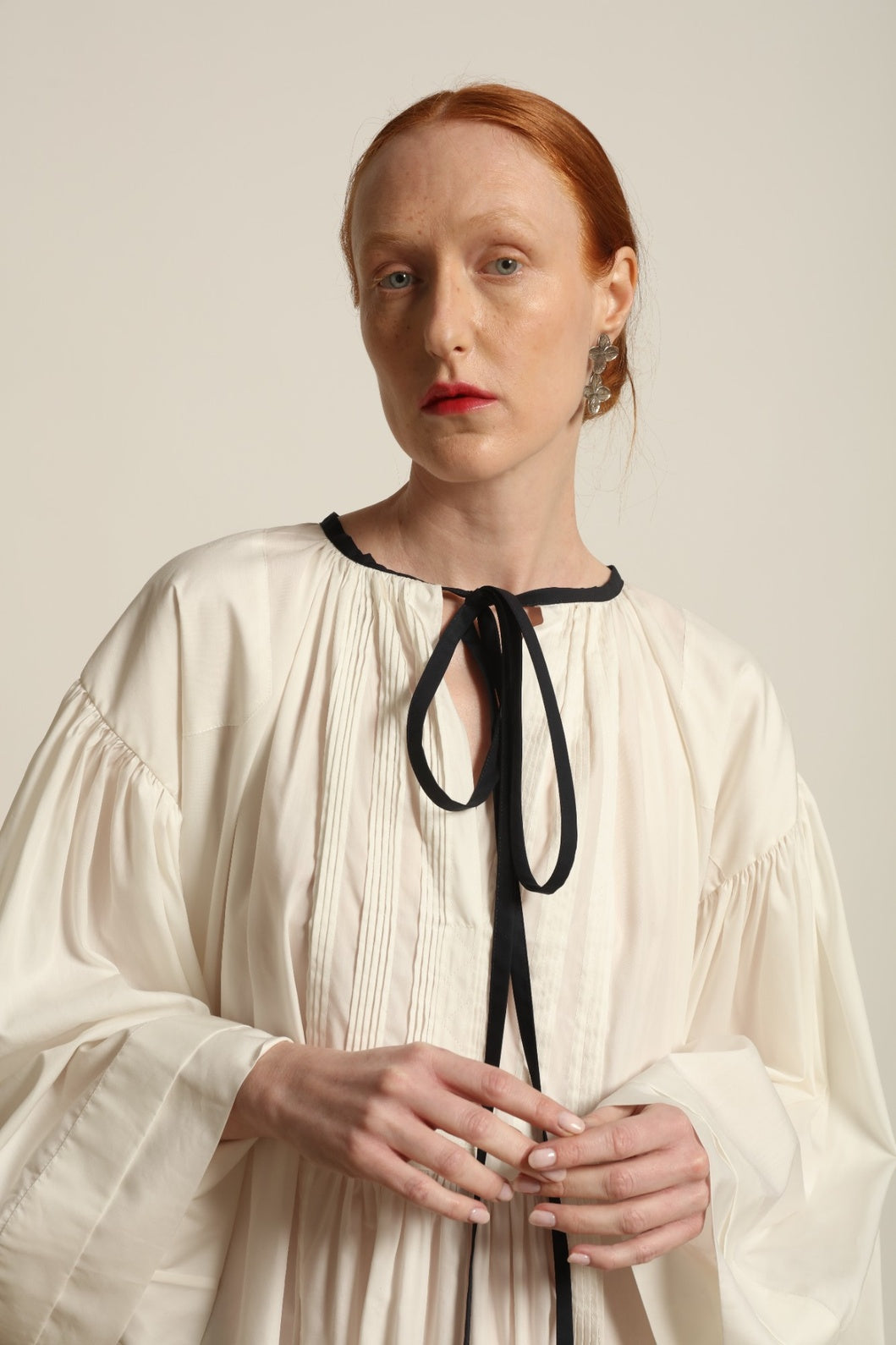 Model is wearing the Les Vacances d’Irina Favignana Dress in White, handcrafted from cotton and silk with multilayered sleeves and hand-sewn pleating, from the House of Nomad Stories selection.
