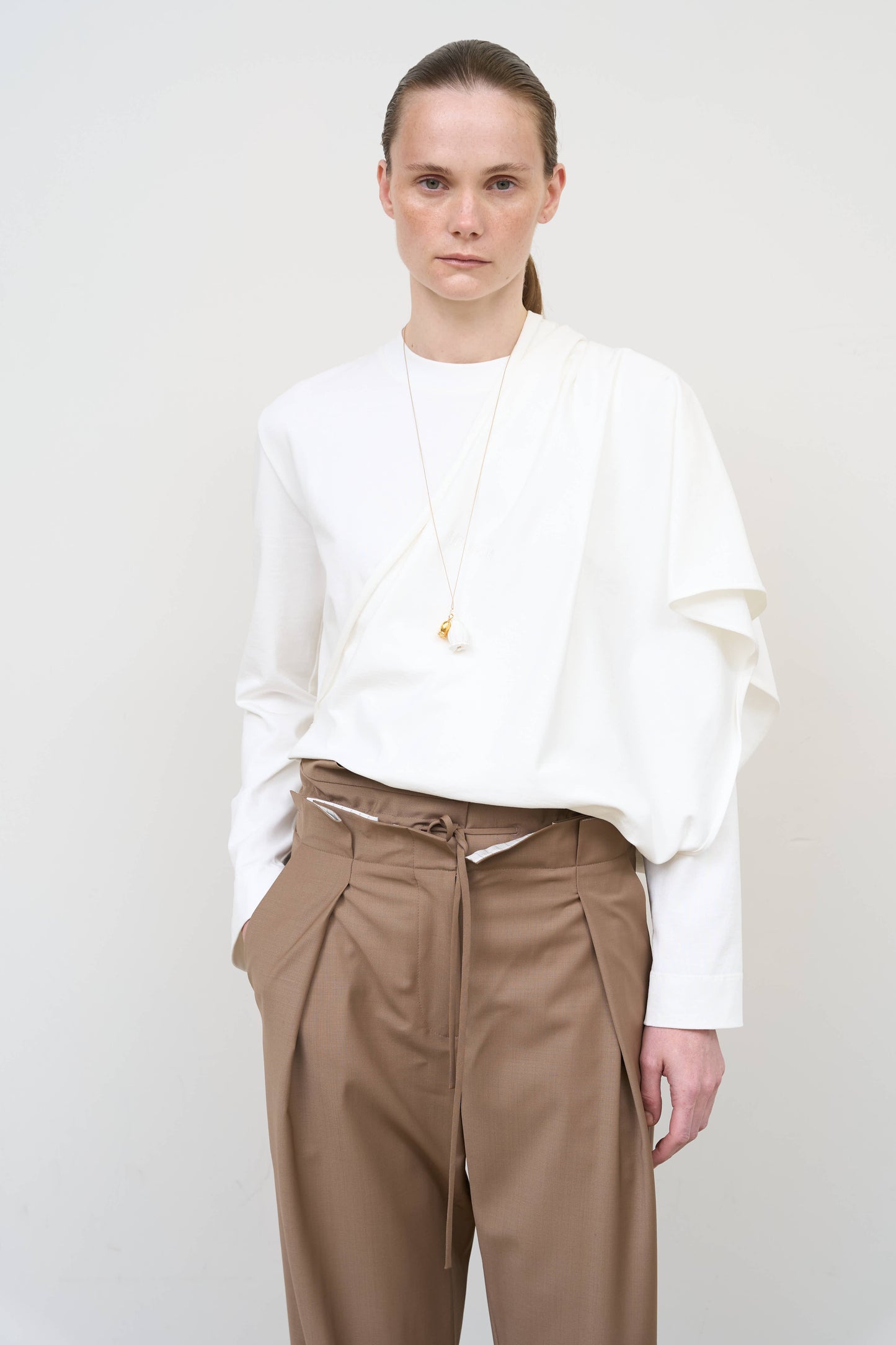 Model is wearing a white asymmetric cotton longsleeve by Litkovska with elongated silhouette and subtle architectural asymmetry, designer women’s top available at House of Woven Stories