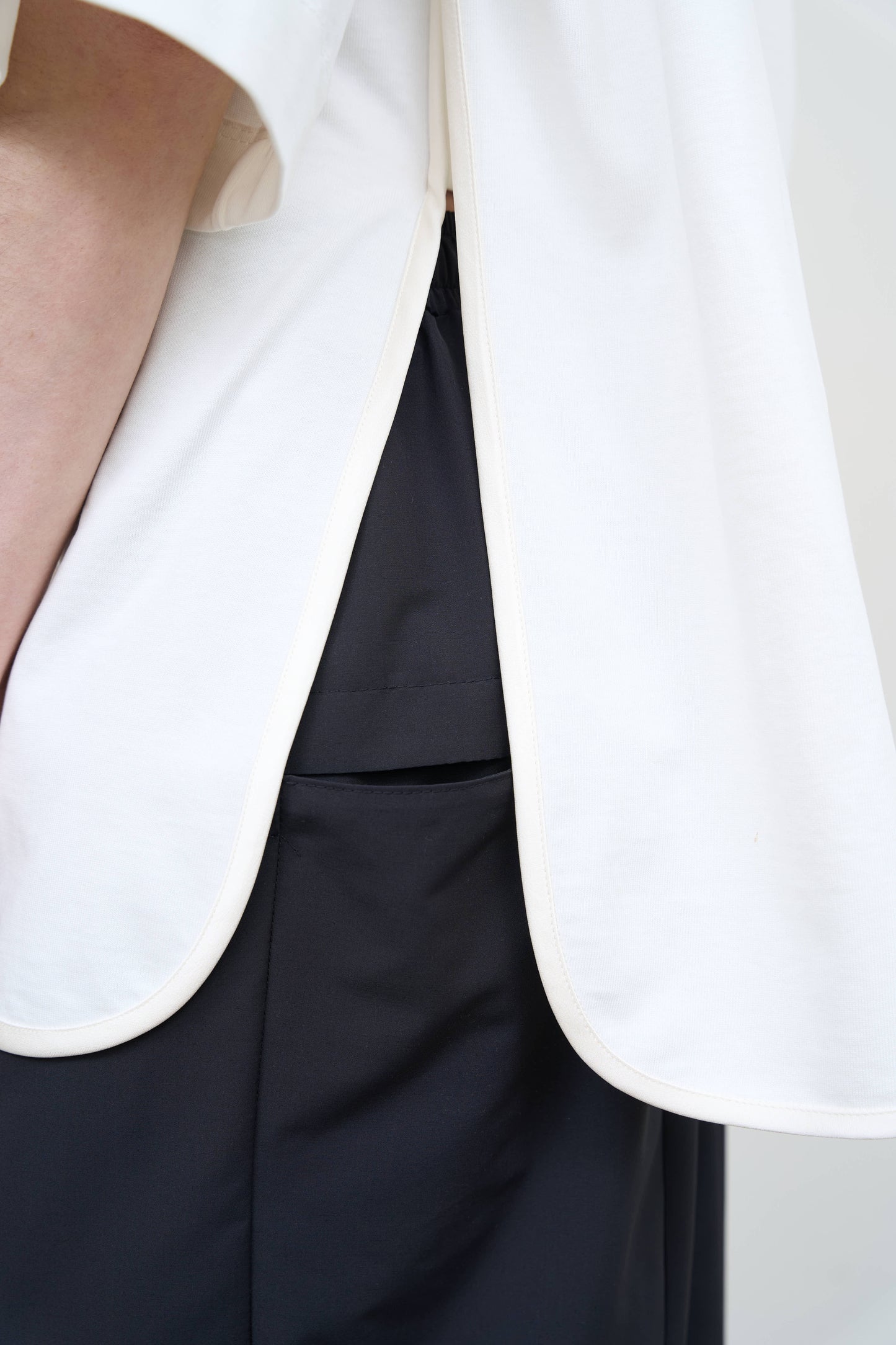 Model is wearing a white Corset T-Shirt by Litkovska with integrated corset-inspired waist panel and relaxed silhouette, designer women’s top available at House of Woven Stories