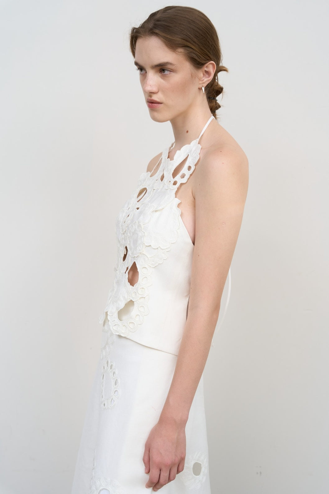 Model is wearing Litkovska white backless top with floral appliqué and sculptural cut-outs. A modern, artisanal, and timeless piece that belongs to the curated selection of House of Nomad Stories.