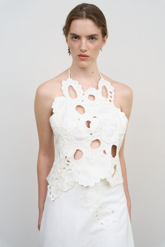 Model is wearing Litkovska white backless top with floral appliqué and sculptural cut-outs. A modern, artisanal, and timeless piece that belongs to the curated selection of House of Nomad Stories.