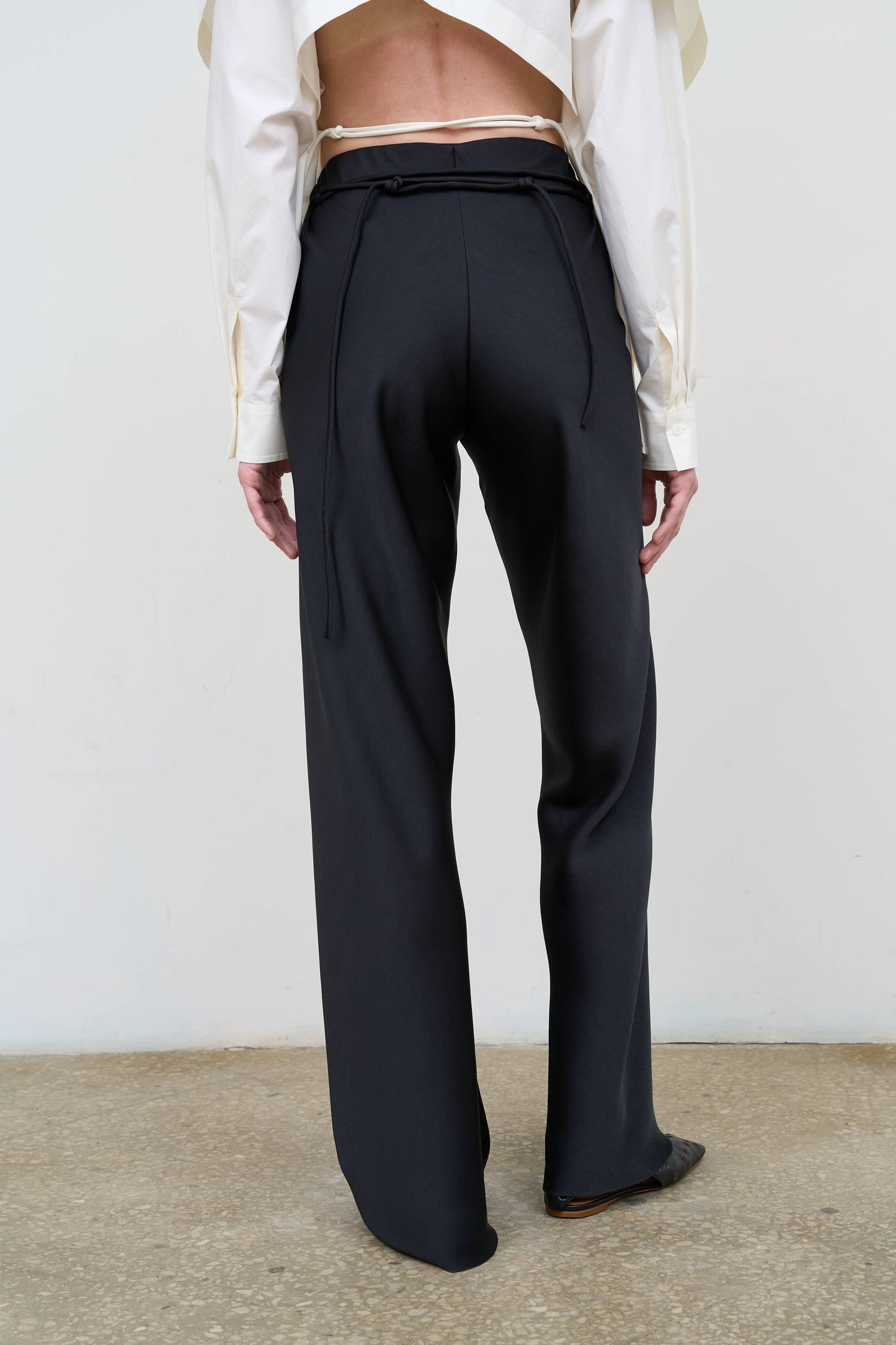 Model is wearing high-rise straight black pants by Litkovska with adjustable waist tie and structured silhouette, designer women’s trousers available at House of Woven Stories