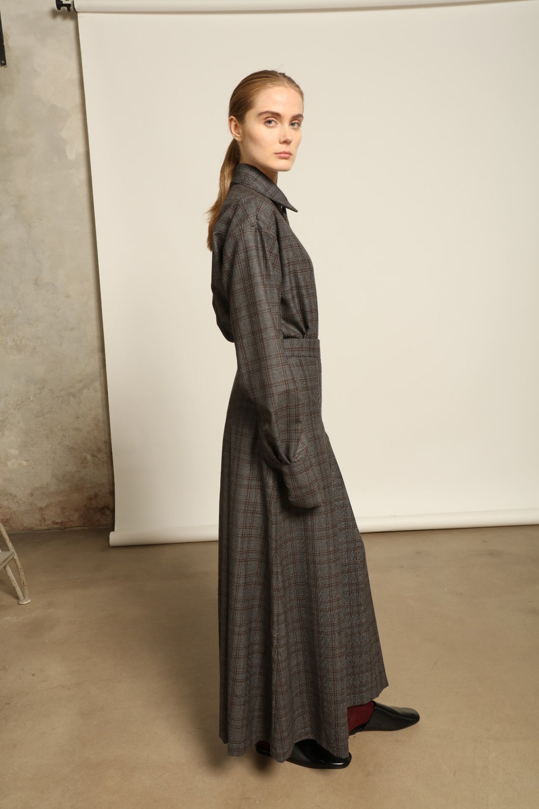 Model is wearing the Londra Brown Checked Skirt by House of Woven Stories, ankle-length with fine pleats and brown checked pattern, combining timeless tailoring with contemporary elegance and quality craftsmanship.