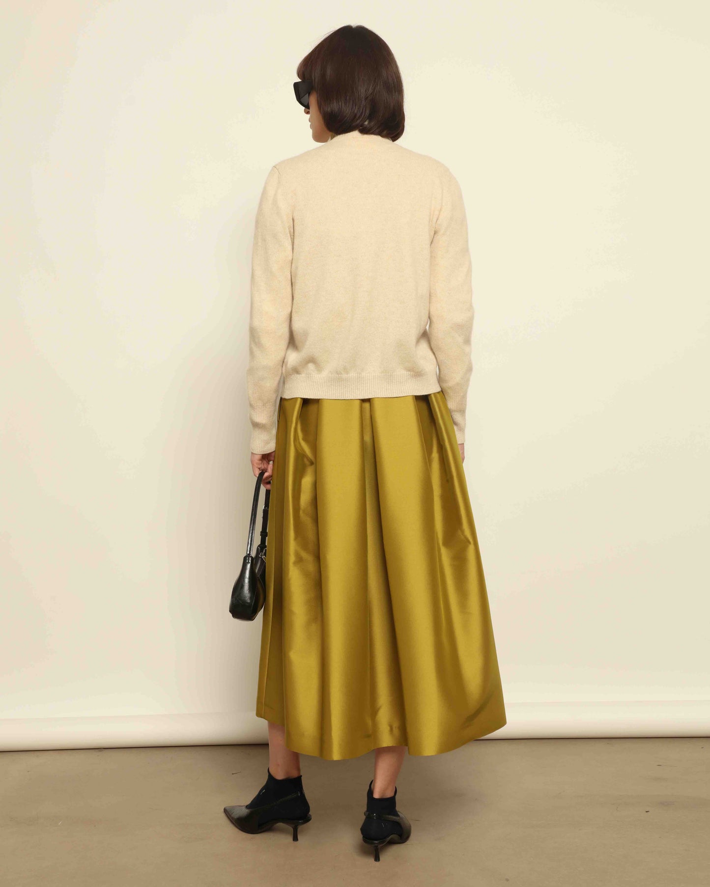 Model is wearing Duchesse Oliva Skirt by Lunatica Milano available at House of Woven Stories. Pleated maxi skirt in a luxurious soft-blend fabric. Elegant, feminine, and handmade in Italy.