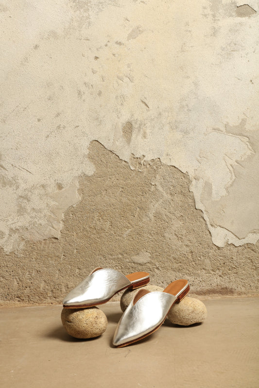 Model is wearing the Majorel Slippers in Silver by House of Woven Stories, handcrafted in Marrakesh from ethically sourced metallic leather with a sleek heel and cushioned insole for modern Moroccan elegance.