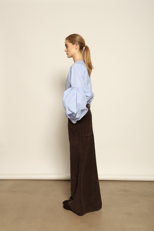 Model is wearing the Maron Foncè Le Pantalon Over Chino by Happy Haus, crafted in soft velour with a wide flowing silhouette, removable belt, back embroidered peacock, and wooden button detail for versatile, relaxed-chic style.