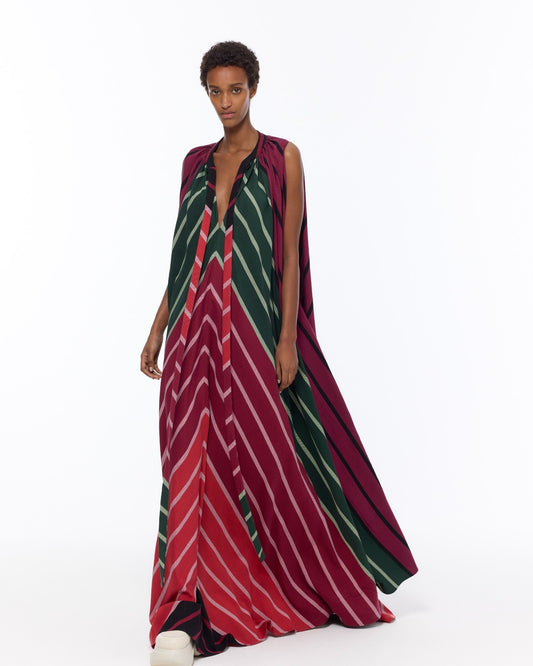 Model is wearing the Cape Dress by Marrakshi Life, a hand-woven striped dress in green and red with adjustable neckline ties and a flowing cape-like silhouette, curated in the House of Woven Stories selection.