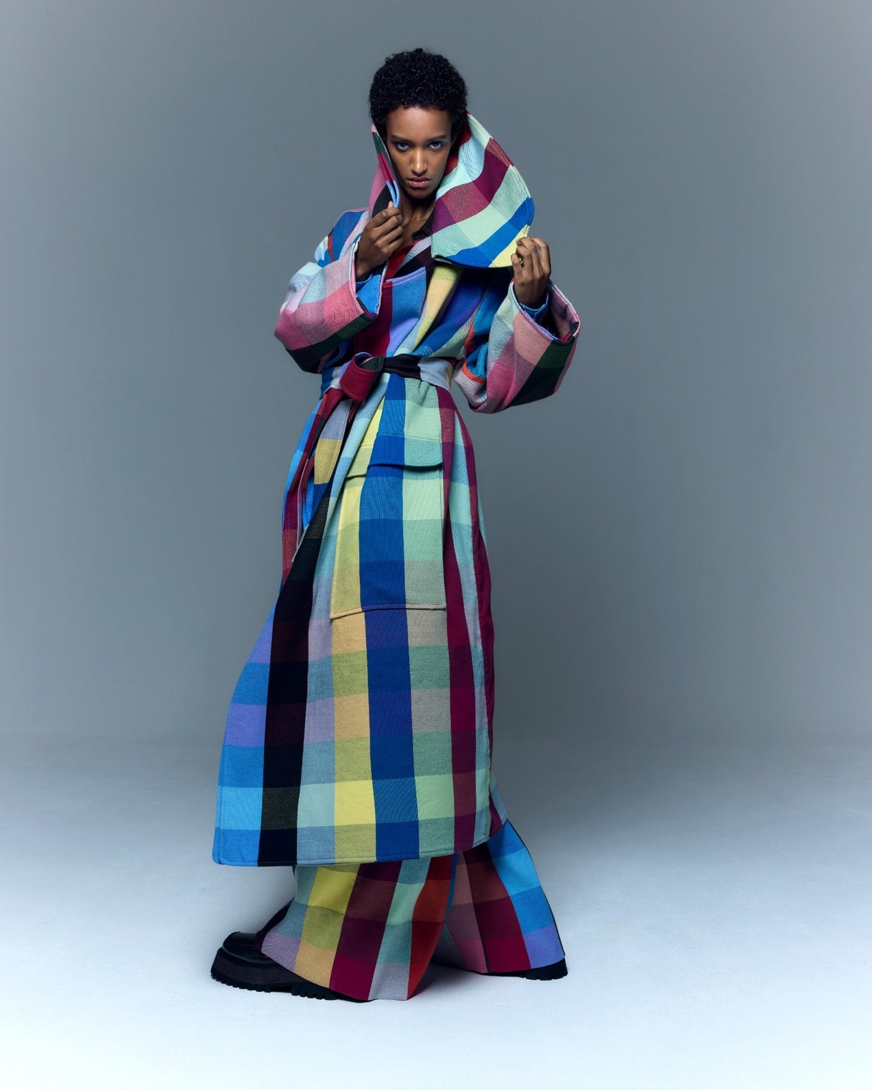 Model is wearing the Double Lapel Overcoat by Marrakshi Life, a hand-woven cotton bouclé coat with oversized plaid, sculptural double lapel and tie belt, curated in the House of Woven Stories selection.