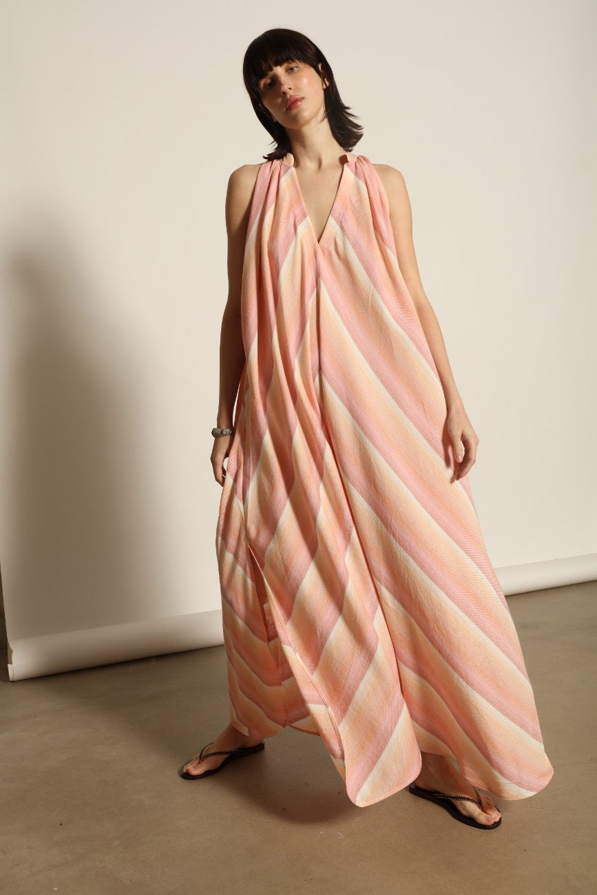 Model is wearing Marrakshi Life halter maxi dress in multicolor striped handwoven cotton, lightweight breathable sleeveless V-neck dress with flowy silhouette and side slits from the curated selection of House of Woven Stories